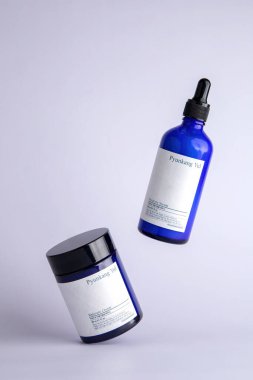 Pyunkang Yul marka krem beyaz arka planda dengelenir. Yakınlarda, mavi cam şişedeki bir serum havaya kalkar.