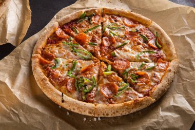 Nefis iştah açıcı pepperonili pizza tütsülenmiş sosis ve siyah arka planda yeşil biber.