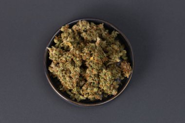 in a bowl dry flowers of medical cannabis on a black background clipart