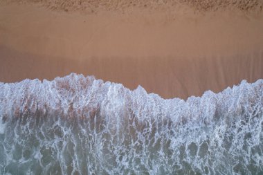 Top Down View of Waves Crashing on Beach. High quality photo. Aerial view shot on the drone DJI Air 2s on Oahu, Hawaii.