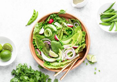 Taze bezelye ve kuşkonmaz ile yeşil yapraklı sulu salata, yukarıdan görmeye hazır.