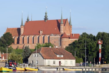 Red brick and roof gothic cathedral on a hill near the edge of a seaport clipart