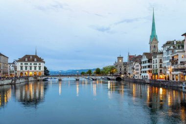 Geceleyin nehir kıyısında tarihi bir mimari köprü ve arka planda uzak dağlar.