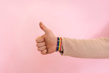 Çeşitlilik, sevgi ve barış için başparmaklar yukarı. Renkli gökkuşağı bilezikli bir el. Gururlu gay. Lezbiyenlik ve geylik kavramı,
