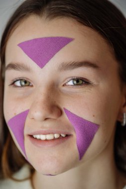Face sealing, close-up of a young girls face with a cosmetic anti-wrinkle tape. Aesthetic sealing of the face with adhesive tape. The concept of facial care.