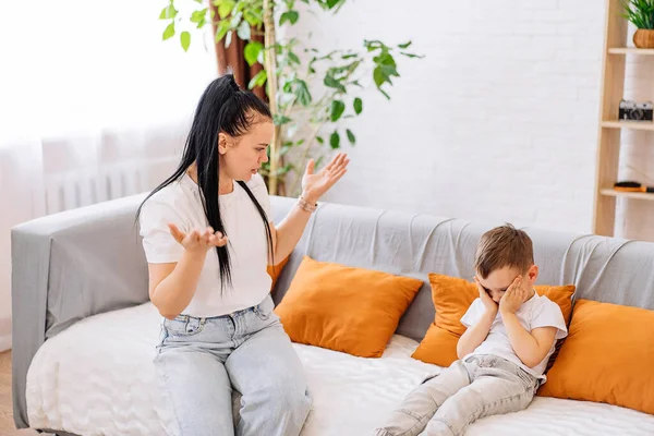 a serious young mother scolds her son for bad behavior, a working mother scolds a screaming child demanding attention. The concept of family conflict.
