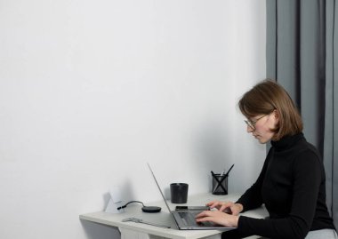 Concentrated woman using laptop at workspace clipart