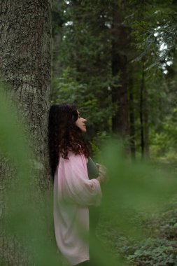Ormanda yeşil yaprak tutan bir kadın. Doğa ahengi ve ruh sağlığı sahnesi
