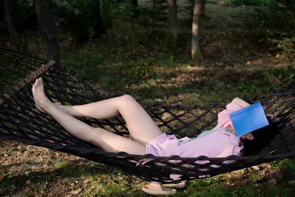 Hamakta kitapla dinleniyor.