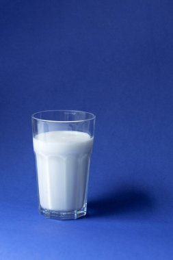 Mavi yüzeyde bir bardak taze süt.