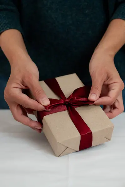 Bir kadının elleri güzel bir hediye paketliyor.