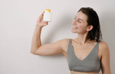 Fit woman holding a container of vitamins clipart