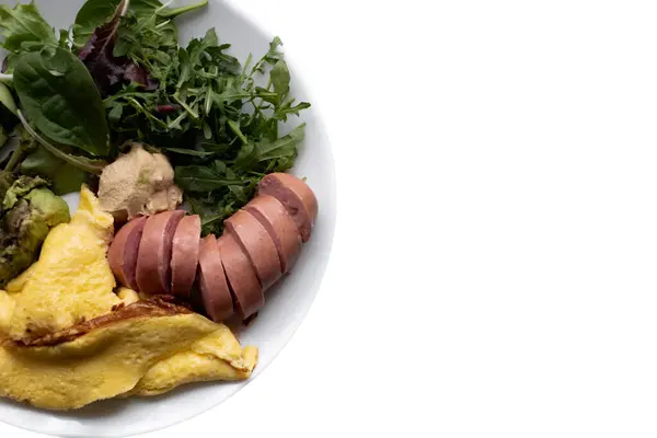 Sağlıklı besleyici kahvaltı tabağı otlu omlet ve sosis, beyaz arka planda izole edilmiş.