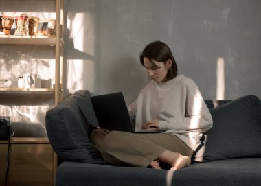 Serbest çalışan biri evde dizüstü bilgisayarla çalışıyor.