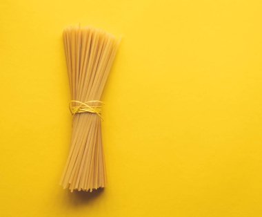 Bunch of spaghetti tied with string on yellow background clipart