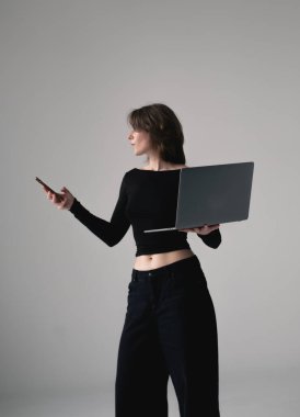 Kendine güveni olan girişimci, iş yerinin yanında dizüstü bilgisayarlı bir telefon tutuyor..