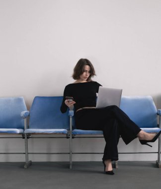 İş kadını dizüstü bilgisayarla bankta oturuyor.