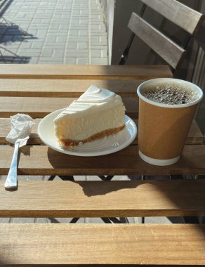 Kahve fincanı ve peynirli kek masada, yaz terasında.