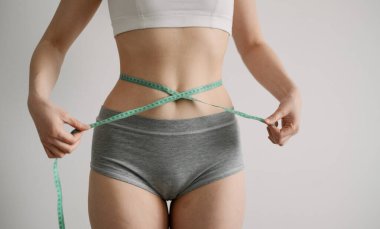 Belini bantla ölçen formda bir kadın.