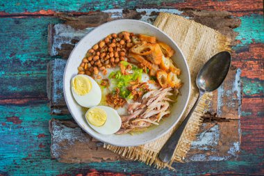 Bubur ayam, Endonezya pirinç lapası dilimlenmiş tavuk haşlanmış yumurta, karides krakeri ve acılı sambal sosuyla servis ediliyor.