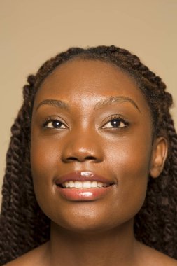 Saçları örgülü gülümseyen bir kadının stüdyo portresi.