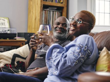 Çift kanepede oturuyor ve şarap içiyor.