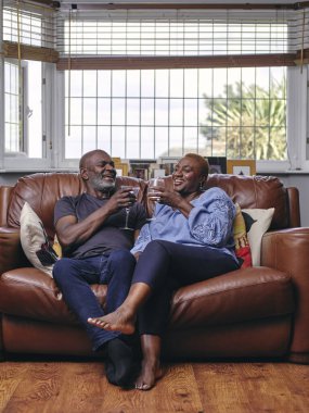 Çift kanepede oturuyor ve şarap içiyor.