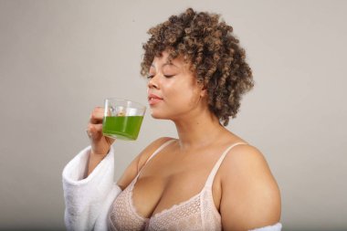 Studio shot of woman in bra smelling green tea