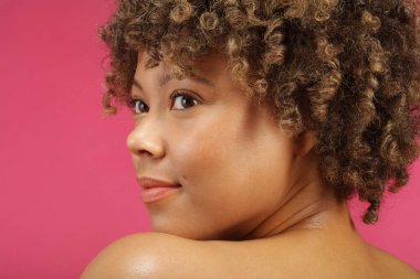 Pembe arka plandaki kadının stüdyo fotoğrafı.