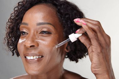 Studio shot of mature woman applying face serum