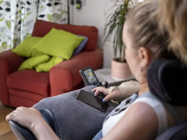 Elektrikli sandalyedeki kadın telefonu kullanıyor.