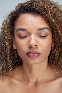 Studio portrait of woman with curly hair and eyes closed