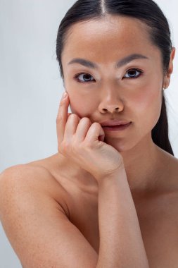 Studio portrait of shirtless woman touching face