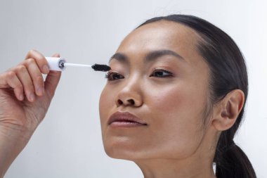 Close-up of woman applying mascara, studio shot