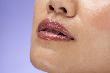 Close-up of woman's lips against purple background