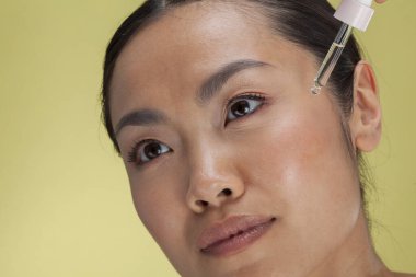 Close-up of woman applying serum on face