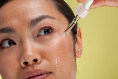Close-up of woman applying serum on face