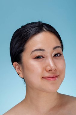 Mavi arka planda gülümseyen kadının stüdyo portresi