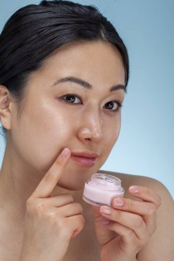 Studio portrait of woman holding facial cream
