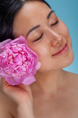 Studio portrait of woman holding pink peony