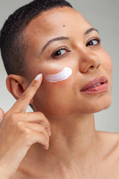 Studio portrait of woman applying facial cream