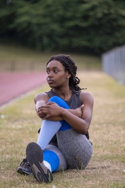 Atletik kadın koşu pistinde bacak esnetiyor