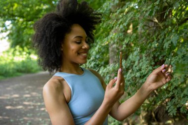 Ormanda akıllı telefon kullanan genç bir kadın