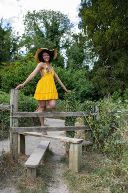 Sarı elbiseli genç kadın çitlere tırmanıyor.