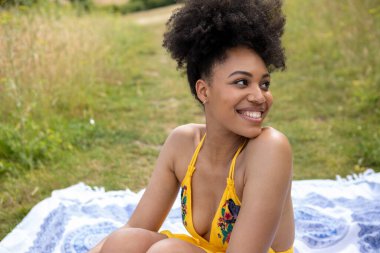 Çayır battaniyesinde dinlenen genç bir kadının portresi.