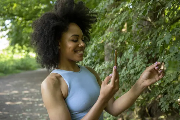 Ormanda akıllı telefon kullanan genç bir kadın