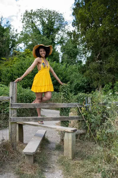 Sarı elbiseli genç kadın çitlere tırmanıyor.