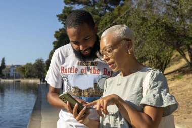 Yazın şehirde akıllı telefon kullanan erkek ve kadın.
