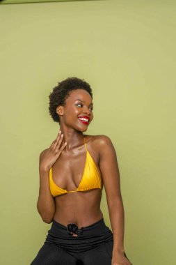 Studio portrait of smiling woman in yellow bikini top