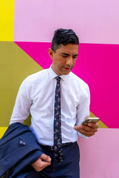 Renkli duvara karşı duran ve telefon kullanan bir işadamı.